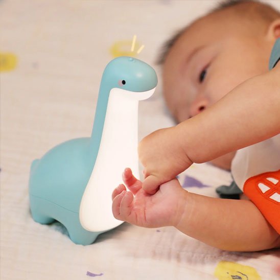 bébé joue avec veilleuse bebe dinosaure bleue