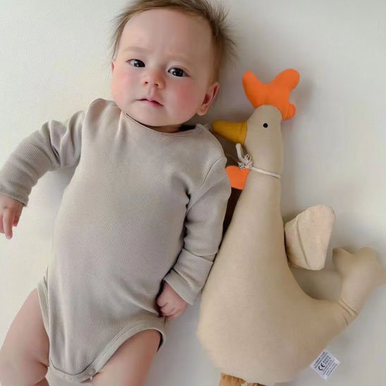 bébé allongé avec doudou poule beige