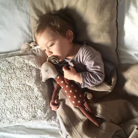 bébé au lit avec doudou marron