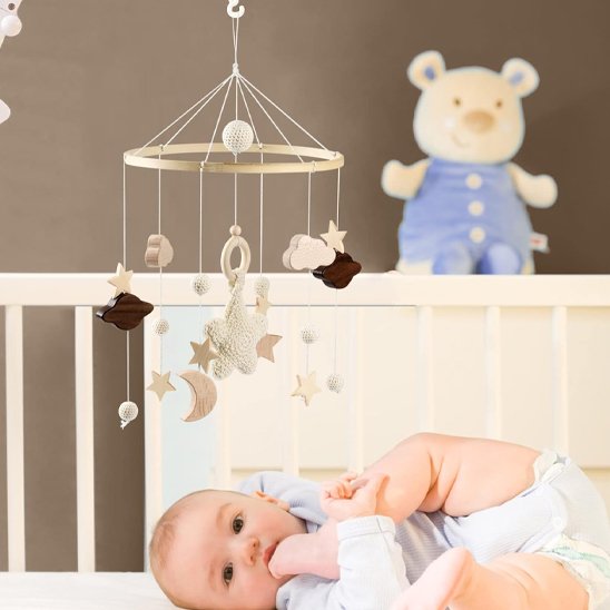bébé dans son lit avec mobile bébé en bois