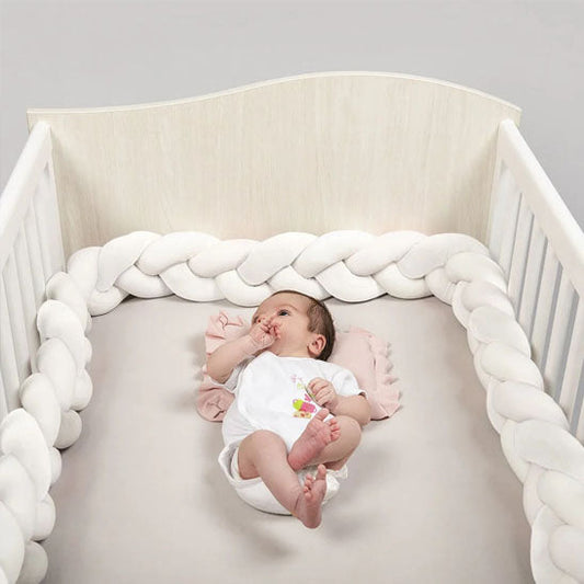 bebe enjoui dans lit avec tresse de lit blanche