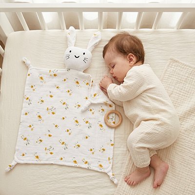 Doudou lapin à fleurs jaunes avec bébé au lit 