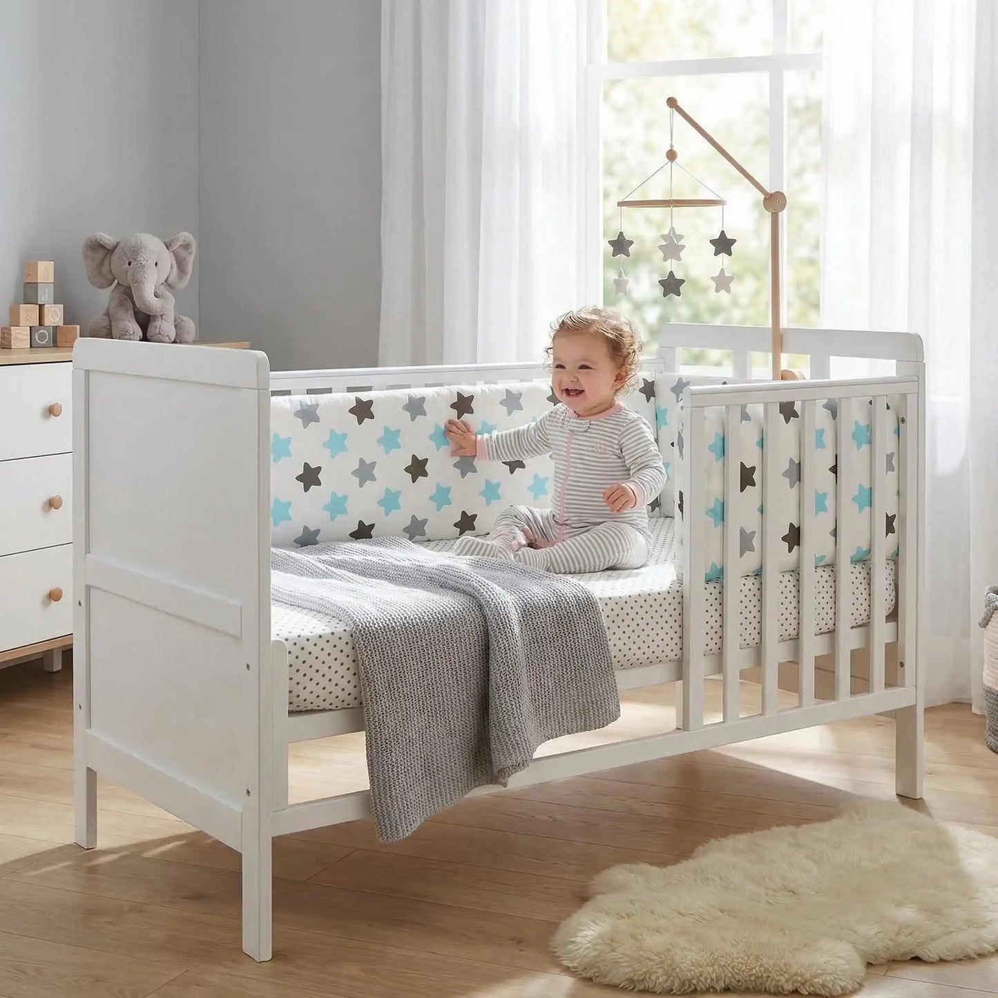 fillette contente assise dans lit touche tour de lit pour bebe