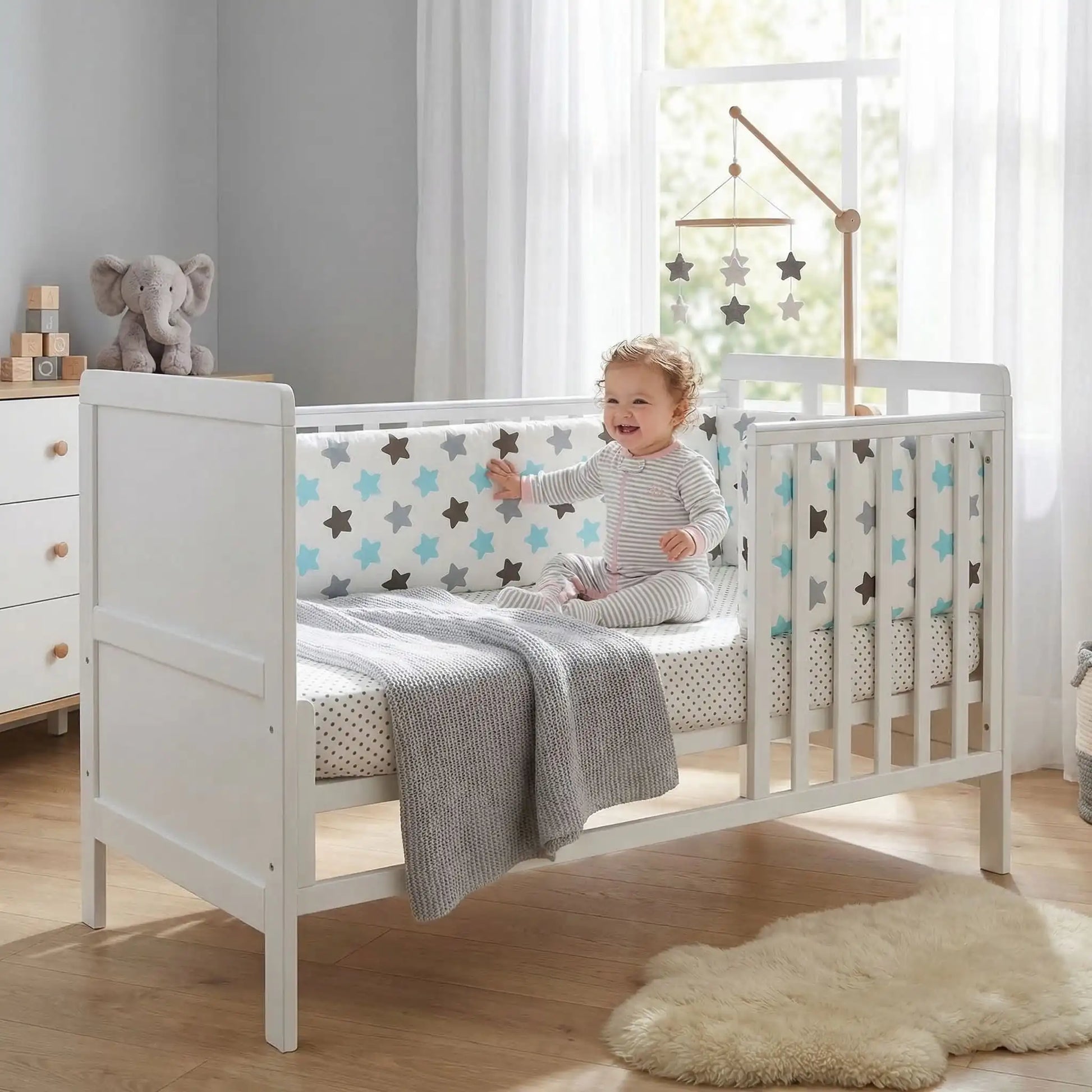 fillette contente assise dans lit touche tour de lit pour bebe
