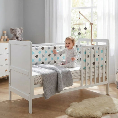fillette contente assise dans lit touche tour de lit pour bebe