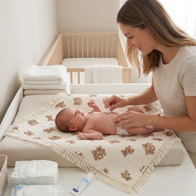 maman change bébé sur couverture bébé naissance